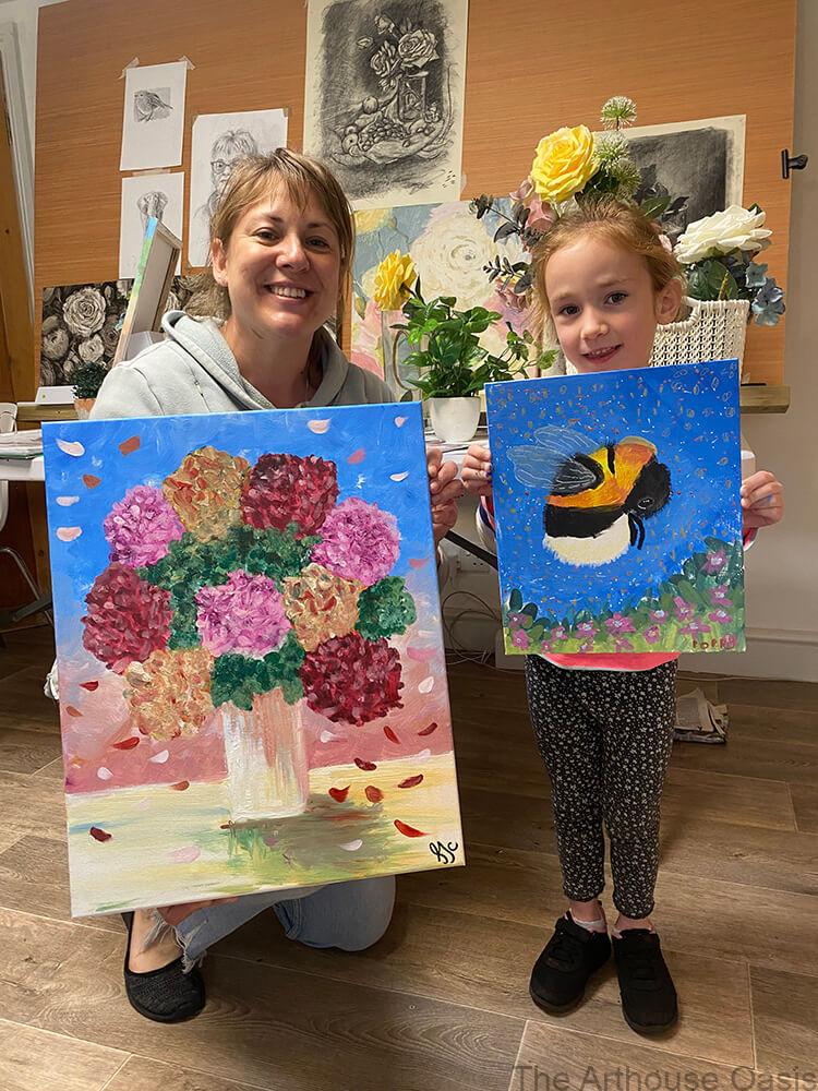 Mother and daughter holding paintings