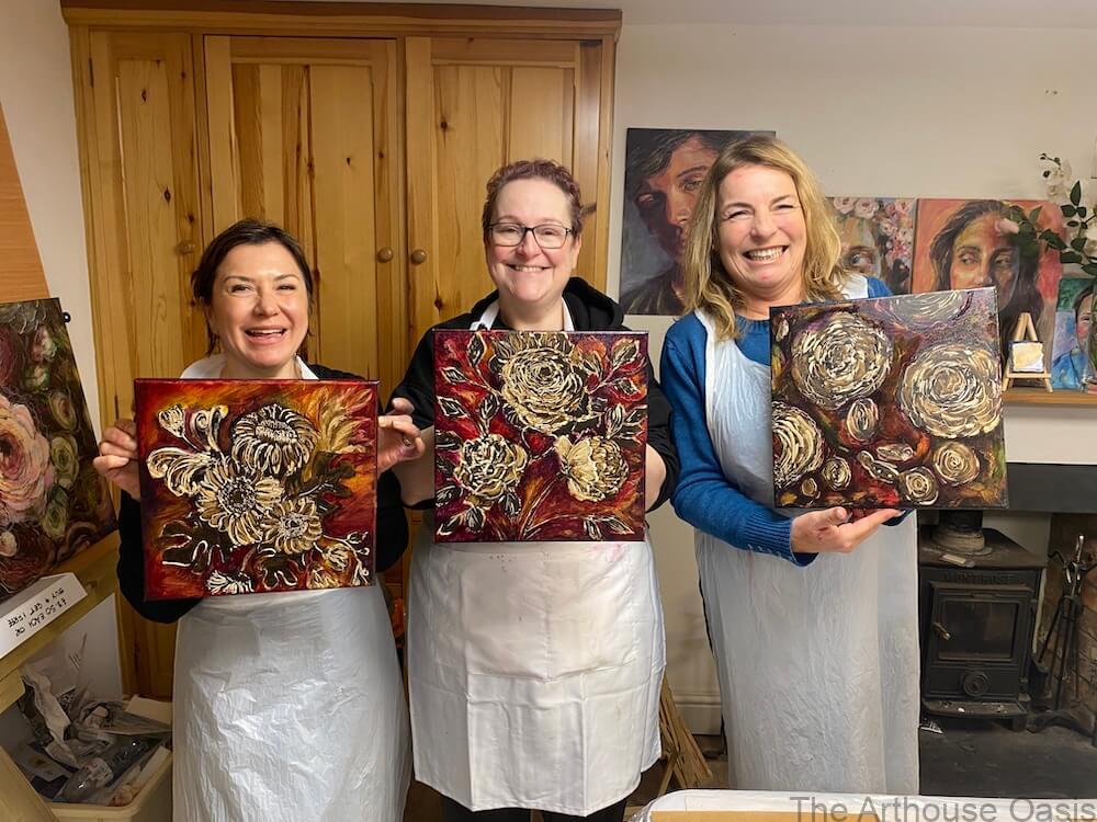 3 artists holding up their oil paintings