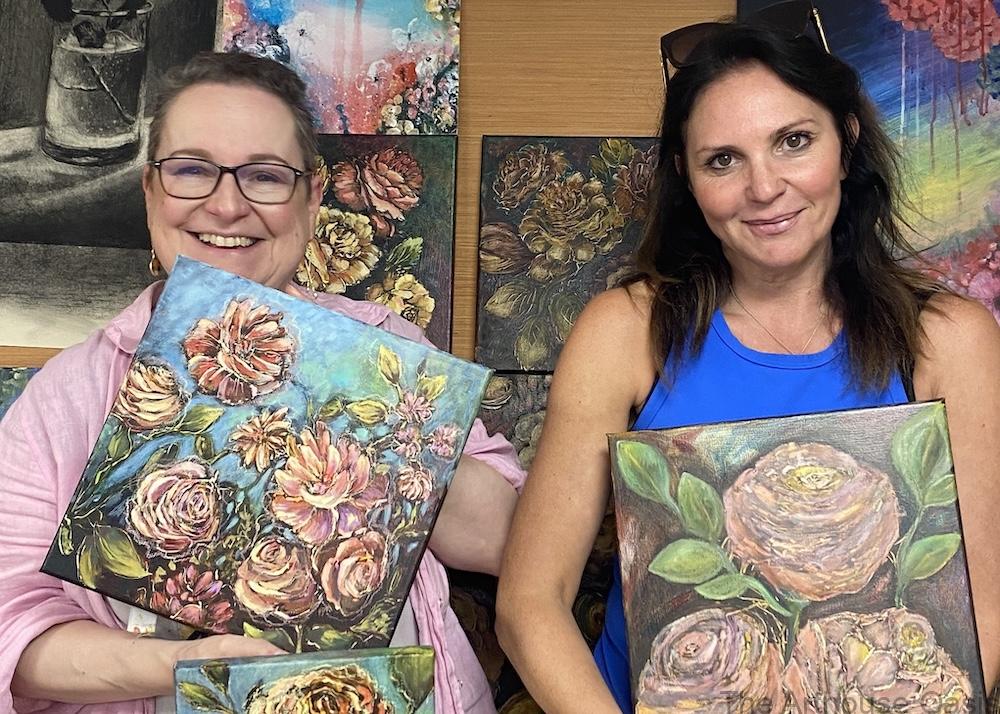 Student and teacher holding 2 oil paintings