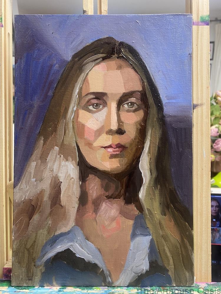 Portrait of a female face against blue background, on easel