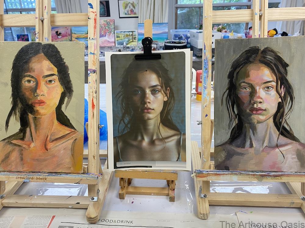Three easels showing two student oil portraits and a photo reference using the Zorn palette in an art class setting.