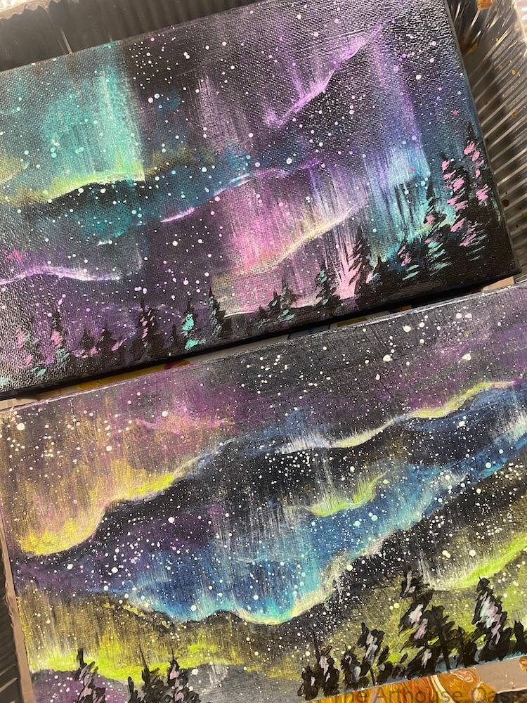 Acrylic paintings of colourful Northern Lights over silhouetted landscapes.