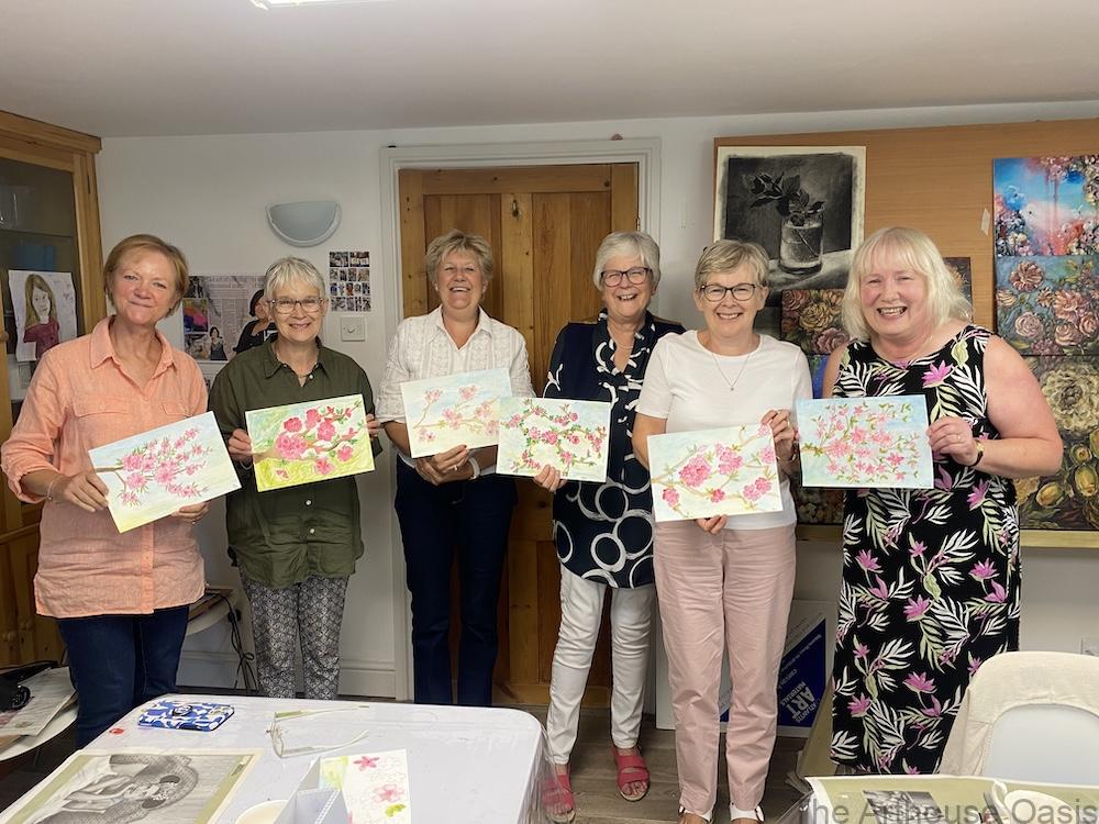 Group of smiling women holding up their finished cherry blossom watercolour paintings