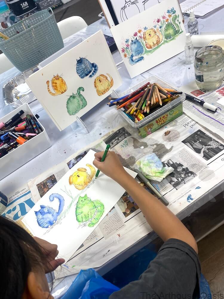 Child painting colourful watercolour cats during a kids’ art workshop in Bishop’s Stortford.