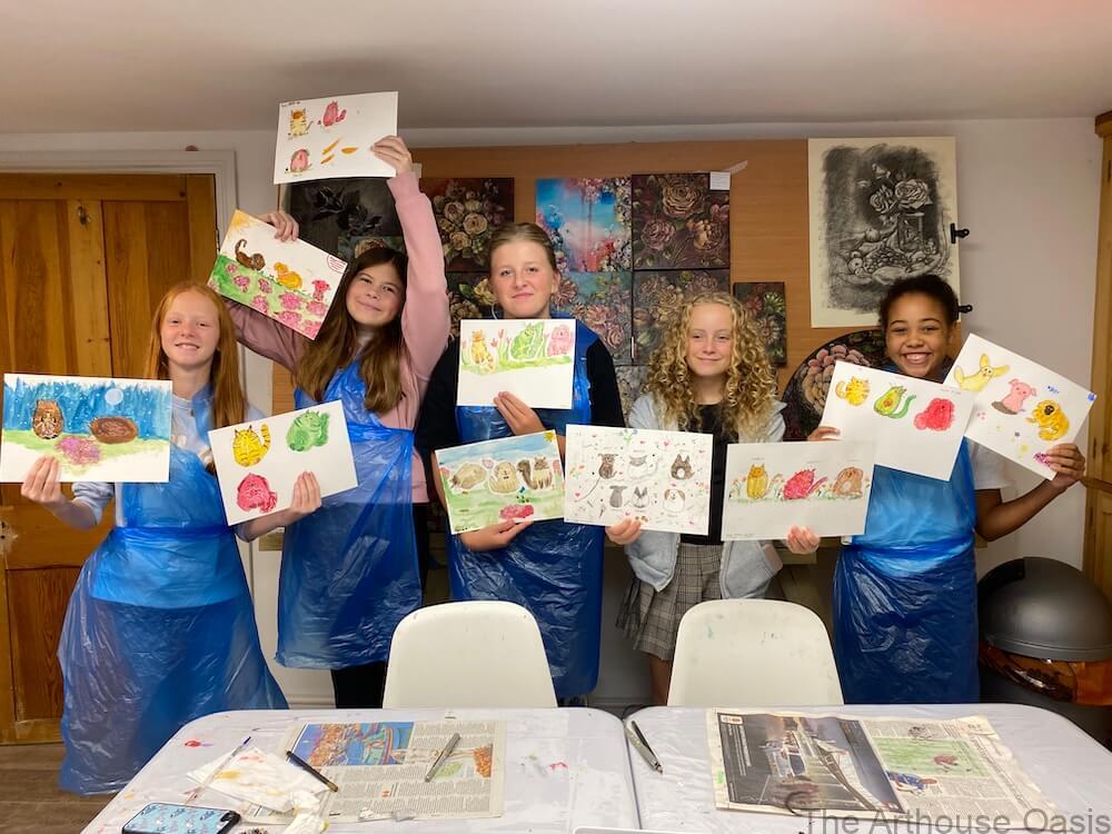 Five smiling children proudly holding up their finished pet watercolour paintings.
