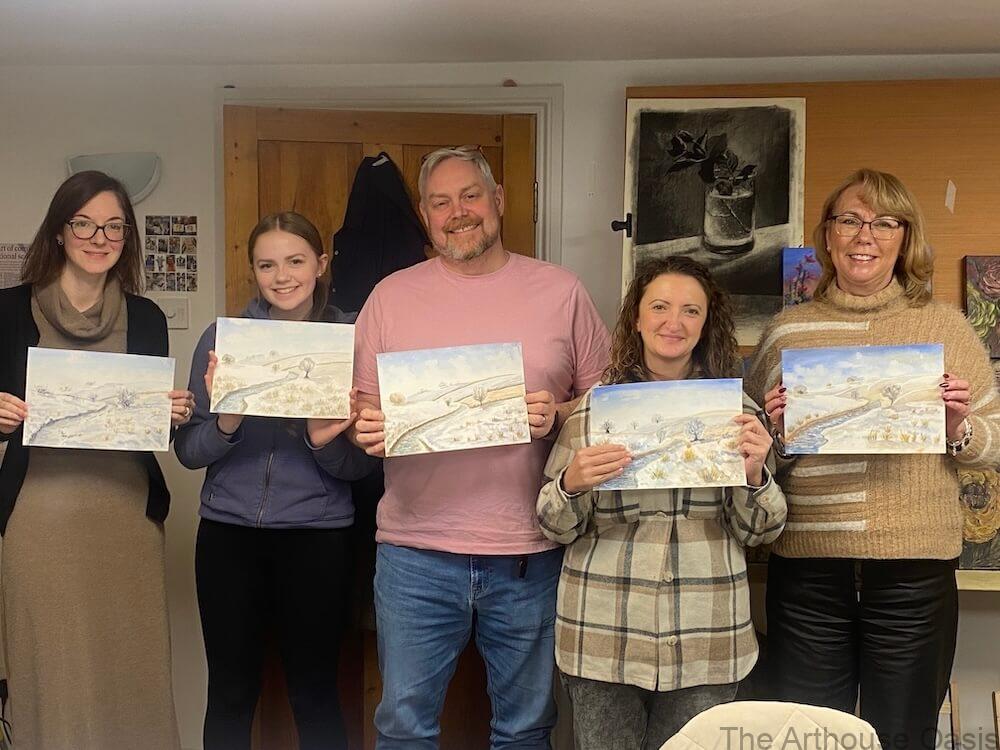 Art students holding finished snow scene watercolour paintings at the end of a winter landscape workshop.