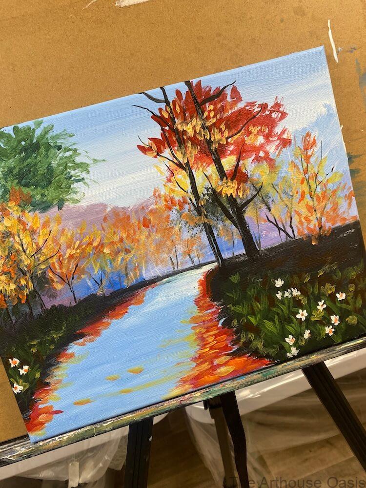 Autumn landscape painting of a river with reflections and colourful trees, created in acrylic during a guided art lesson