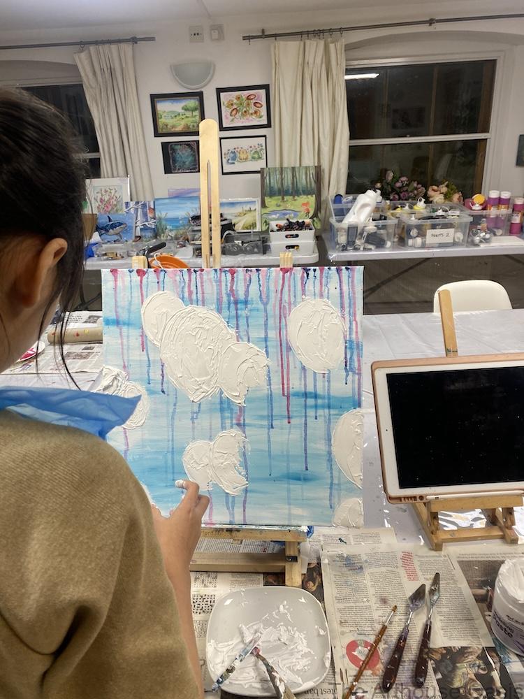 Young art student creating a colourful textured balloon artwork using mixed media techniques.