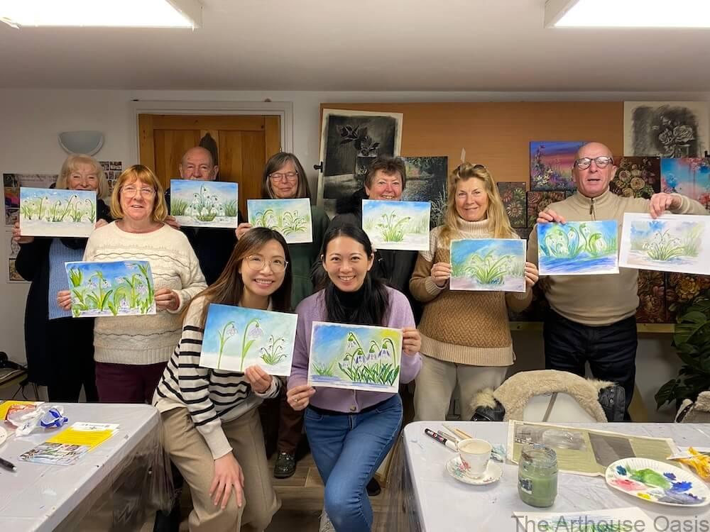 Group of adult art students holding their finished snowdrops watercolour paintings.