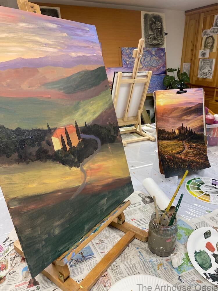Acrylic landscape painting inspired by Tuscany with hills, trees and sunset light on canvas in an art studio.