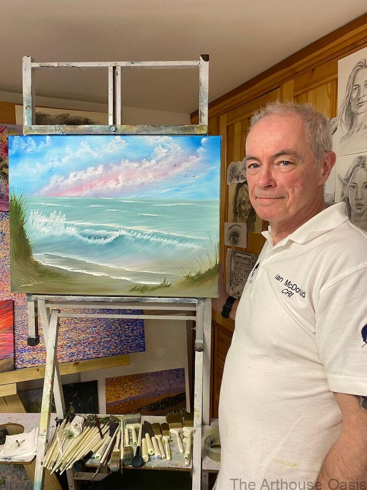 Art student holding up Bob Ross seascape oil painting