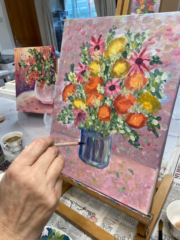 Acrylic painting of a colourful flower arrangement in a glass jar on a pink background in an art class.