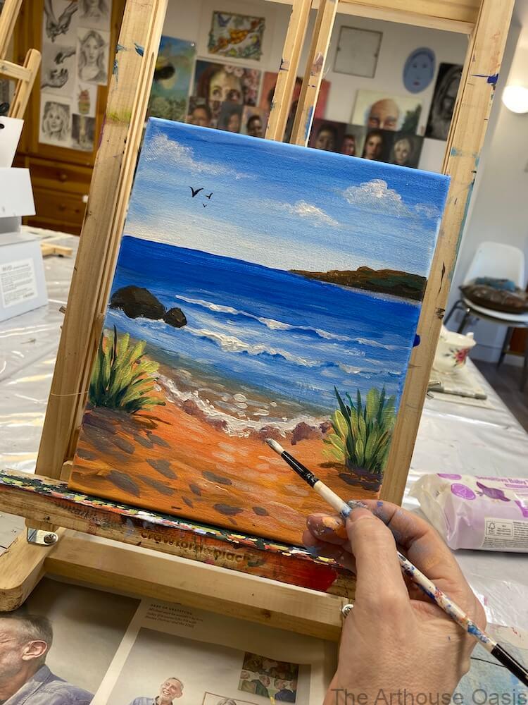 Finished acrylic seascape painting with sandy beach, waves and coastal plants.