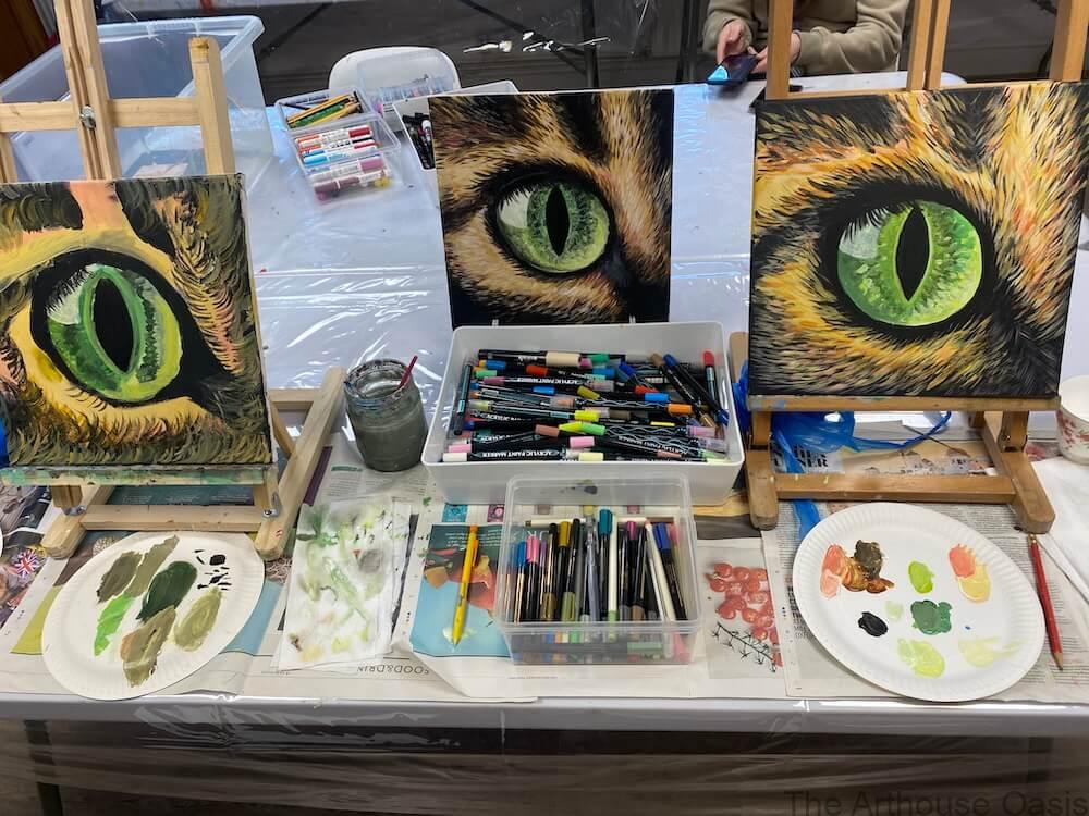 Three acrylic cat eye paintings showing green eyes and layered fur textures.