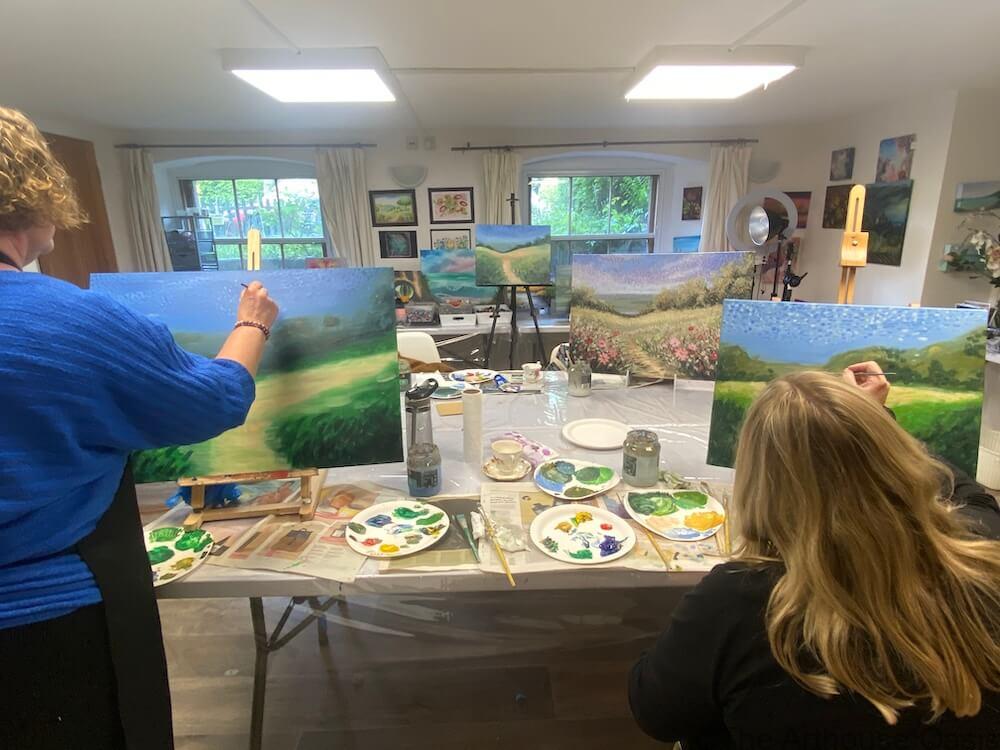 Students working on impressionist landscape paintings during an art class.