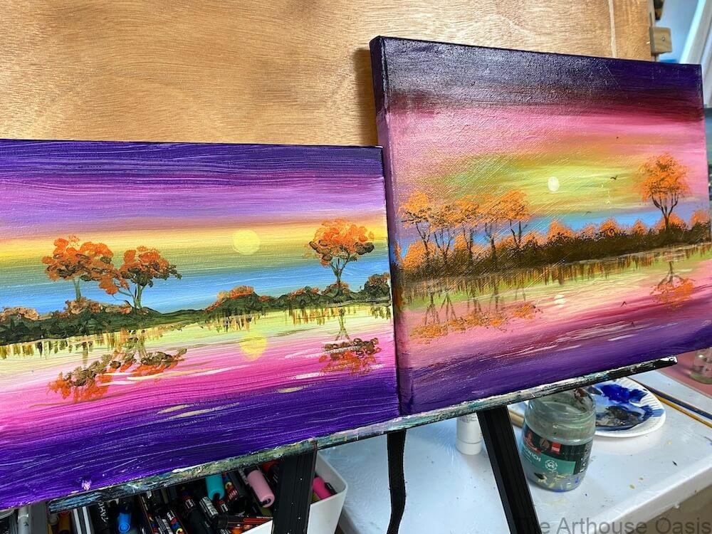 Two completed acrylic sunset landscape paintings displayed side by side after class.