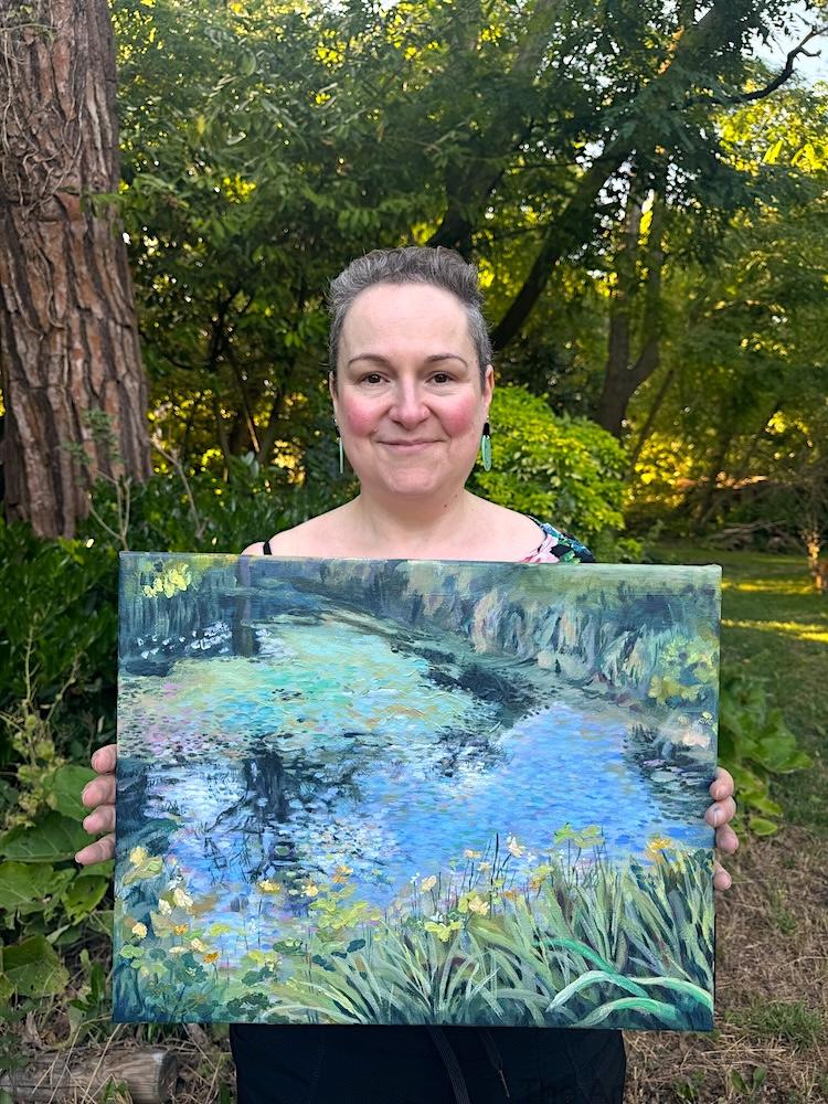 Artist holding the original Glebe House Reflections acrylic painting in a woodland garden